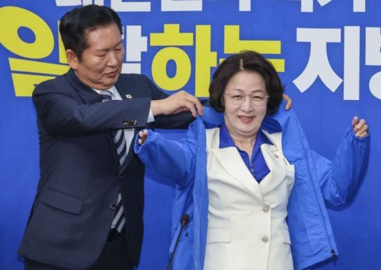 더불어민주당 정청래 대표가 지난 13일 최고위원회의에 앞서 열린 추미애 경기도지사 후보 환영식에서 추 후보에게 선거용 점퍼를 입혀주고 있다. 연합뉴스