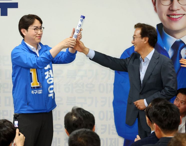 부산 북갑 국회의원 보궐선거에 출마하는 더불어민주당 하정우 후보가 10일 오후 부산 북구에서 열린 선거사무소 개소식에서 전재수 부산시장 후보가 건넨 '북구의 미래'가 적힌 바톤을 넘겨 받고 있다. 연합뉴스