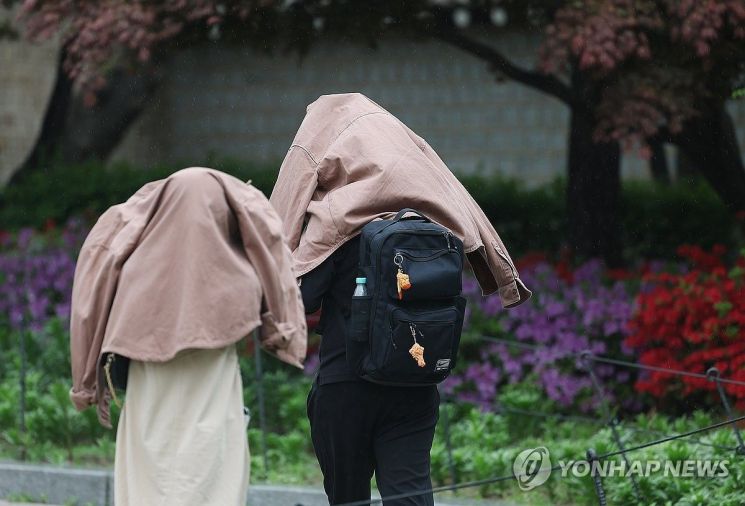 서울에 비가 내린 20일 서울 종로구 경복궁 인근에서 외국인 관광객들이 겉옷으로 비를 피하고 있다. 연합뉴스