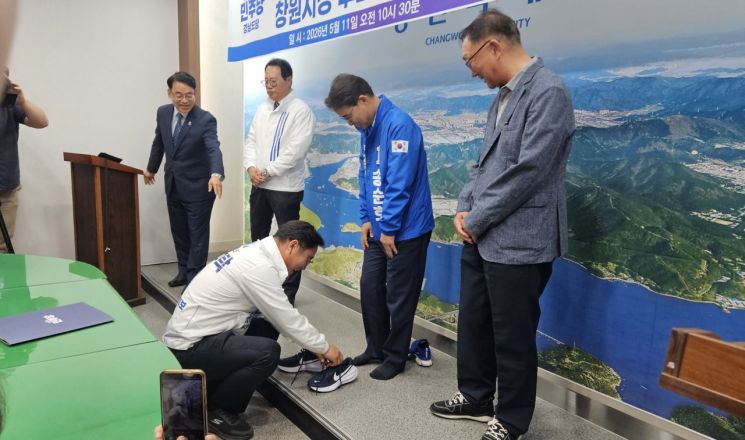 경남 창원특례시장 후보로 나선 조국혁신당 심규탁 후보가 더불어민주당 송순호 후보와의 단일화 선언 후 송 후보의 발에 운동화를 신겨주고 있다. [사진=이세령 기자]