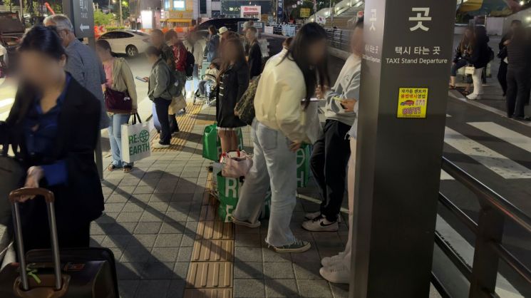 지난 7일 새벽 지하철 막차가 끊기자 서울역 택시 승강장 인근에서 외국인 관광객들이 택시를 잡기 위해 핸드폰 화면을 바라보며 기다리고 있다. 박호수 기자