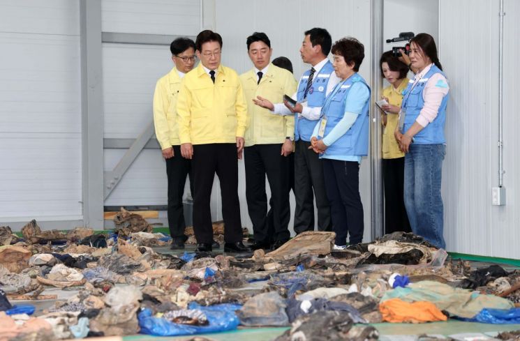 이재명 대통령이 18일 전남 무안국제공항 제주항공 참사 유류품 보관소에서 설명을 듣고 있다. [청와대통신사진기자단] 연합뉴스
