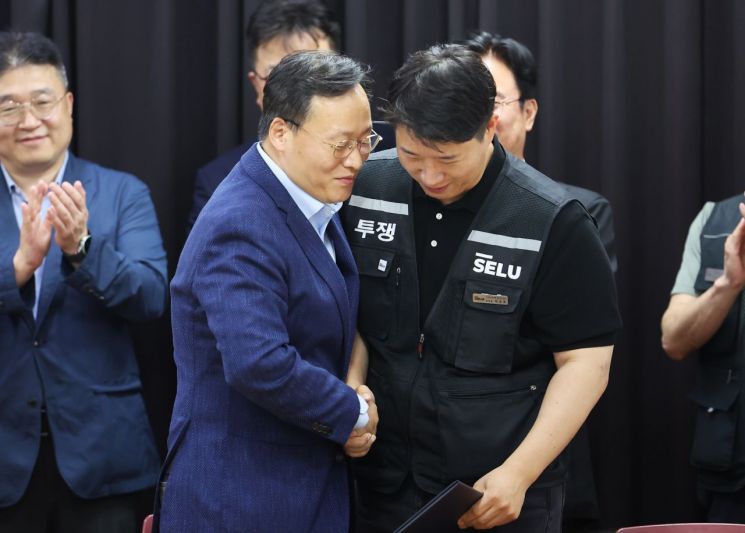 20일 경기도 수원시 장안구 경기고용노동청에서 열린 삼성전자 임금협상을 마친 후 여명구 삼성전자 DS(디바이스솔루션·반도체 사업 담당) 피플팀장과 최승호 삼성그룹 초기업노동조합 삼성전자지부 위원장이 잠정 합의안에 서명한 후 손을 맞잡고 있다. 연합뉴스