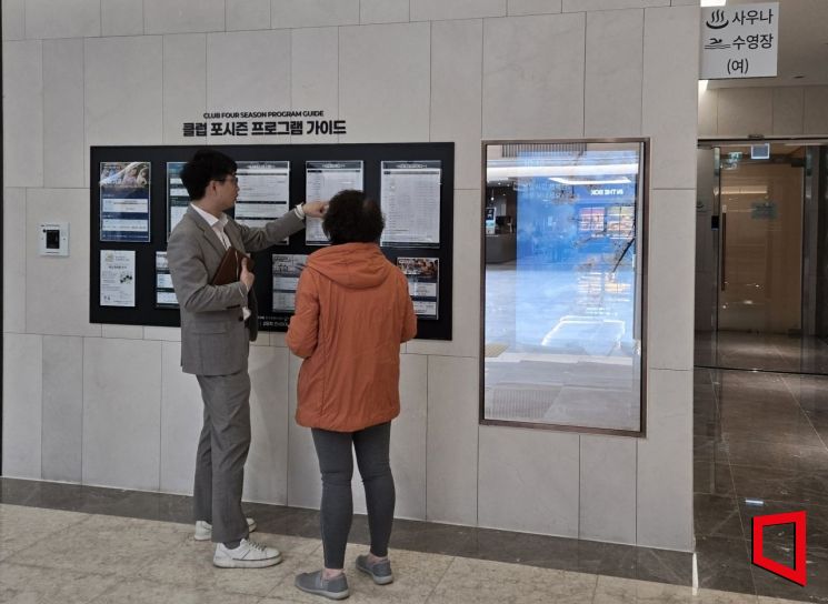 경기 의왕시 '백운호수 푸르지오 숲속의 아침' 커뮤니티광장에 마련된 프로그램 안내판 앞에서 강태건 엠포레 대표가 입주민에게 프로그램 일정을 설명하고 있다. 최서윤 기자