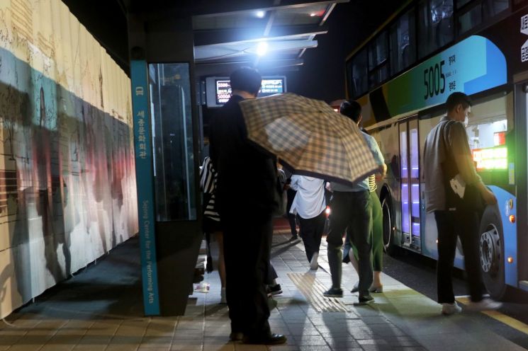 2021년 6월, 비 오는 날 버스정류장에서 퇴근길 한 가장이 무심코 그림을 바라보고 있다.