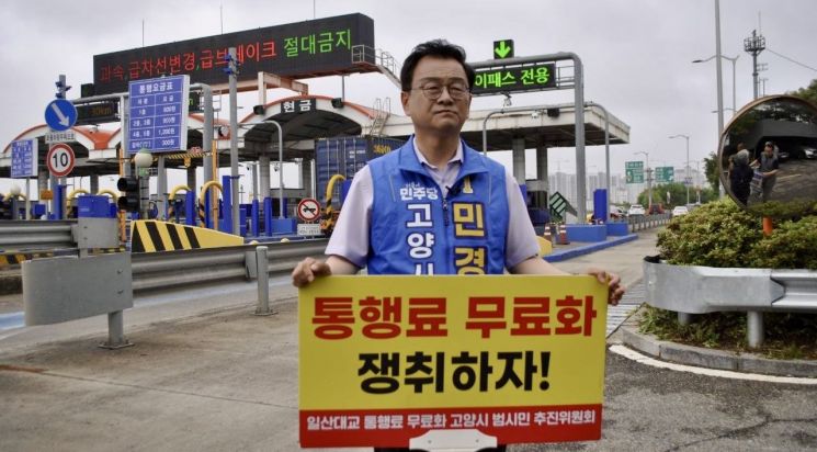 민경선 고양시장 후보가 일산대교 톨게이트 앞에서 통행료 무료화 피켓을 들고 1인시위를 하고 있다. 민경선 후보 제공