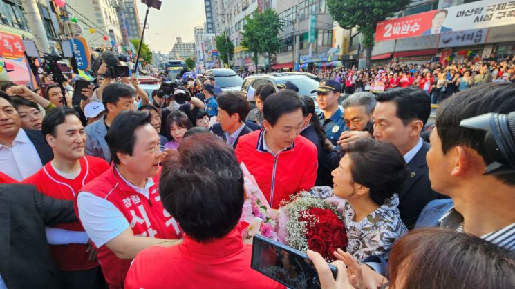 박근혜 전 대통령이 지지자로부터 꽃다발을 받아든 채 국민의힘 후보와 경남도당 관계자들과 인사하고 있다. [사진=이세령 기자]