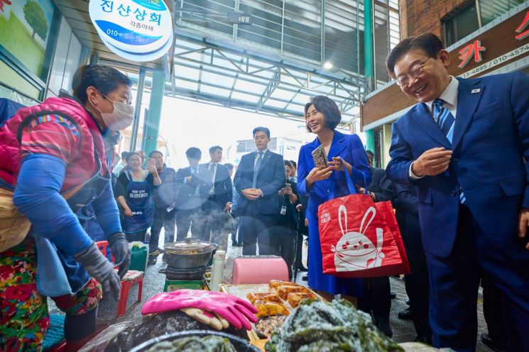 President Lee Jae-myung and First Lady Kim Hye-kyung are seen conversing with merchants at Busan Namhang Market on the 27th. [Image source=Yonhap News Agency]