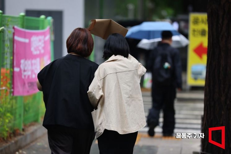 시민들이 우산 대신 종이봉투를 쓰고 걸어가고 있다. 윤동주 기자