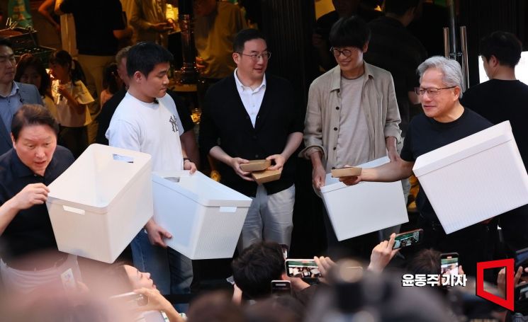 5일 서울 마포구 서교동의 한 고깃집에서 젠슨 황 엔비디아 최고경영자(CEO)와 최태원 SK회장, 구광모 LG회장, 이해진 네이버 의장이 삼겹살 회동 도중  시민들과 취재진에게 바나나우유와 붕어빵 등 간식을 나눠주고 있다. 윤동주 기자
