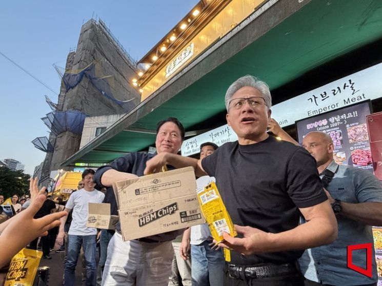 젠슨 황 엔비디아 최고경영자(CEO)와 최태원 SK그룹 회장이 5일 서울 마포구 홍대 인근 삼겹살 음식점 '형님 저요' 앞에서 시민들과 취재진에게 HBM칩스 과자를 나눠주고 있다. 장보경 기자