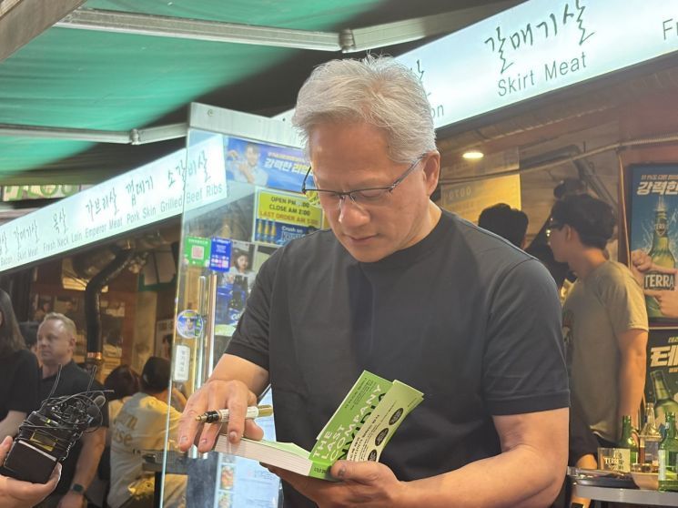젠슨 황 엔비디아 최고경영자(CEO)가 5일 시민이 건넨 책에 서명을 하고 있다. 장보경 기자