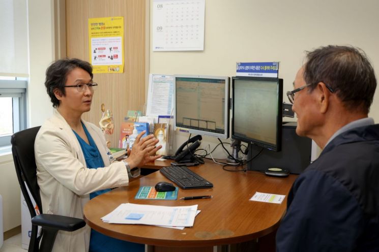 서울성모병원 비뇨의학과 홍성후 교수(오른쪽)가 하대정맥 혈전을 동반한 3기 신장암 고령 환자(왼쪽)를 국내 처음으로 후복막 단일공 로봇을 활용해 수술 후 첫 외래를 찾은 환자와 사진을 촬영하고 있다. 서울성모병원