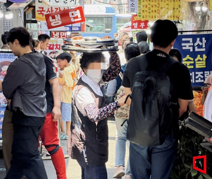 44년째 남대문시장에서 쟁반 배달 일을 하고 있는 오희자씨(76)가 지난 16일 서울 중구 남대문시장 갈치골목에서 머리에 양은 쟁반을 이고 배달에 나서고 있다. 박호수 기자