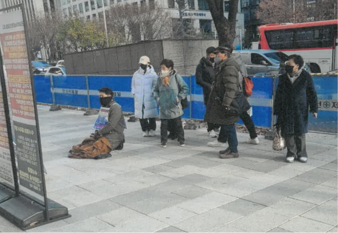 손영서 변호사가 김씨가 수술받은 병원 앞에서 무릎을 꿇고 1인 시위를 하는 모습.