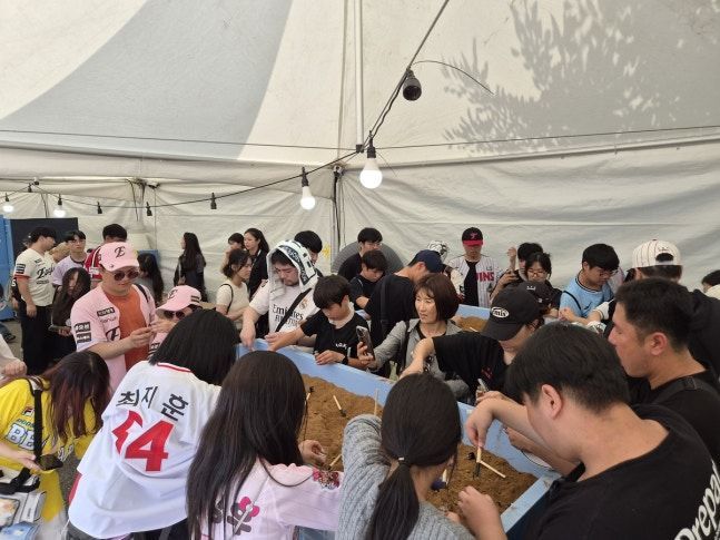 지난 11일 오후 2시 서울 잠실종합운동장 2주차장에 마련된 팬 페스트존의 'Re:member 부스에선 팬들이 공병에 차곡차곡 흙을 담고 있다. 연합뉴스