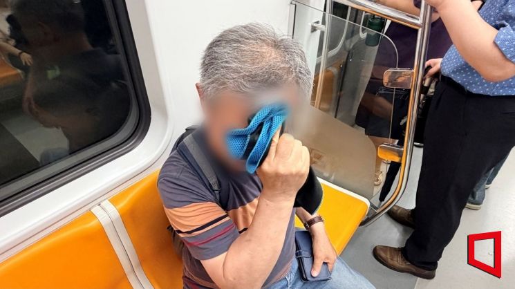 지난 2일 오전 8시께 지하철 2호선 안에서 실버 택배원 김모씨(72)가 연신 손수건으로 땀을 훔치고 있다. 이지예 기자
