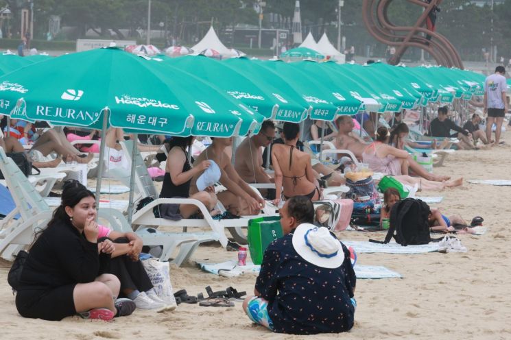 연일 무더위가 이어지는 가운데, 부산 해운대해수욕장을 찾은 시민과 관광객들이 파라솔 아래에서 휴식을 취하며 한여름 해변의 여유를 즐기고 있다. 연합뉴스