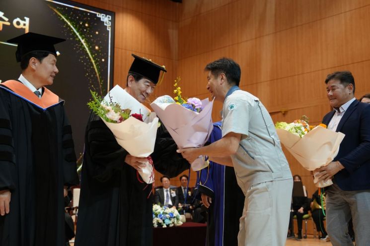 SNT다이내믹스와 SNT에너지 노조 지회장이 최평규 회장에게 축하 꽃다발을 전달하고 있다.