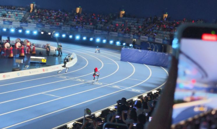 22일 중국 베이징 국가스피드스케이팅경기장에서 열린 제2회 세계 휴머노이드 로봇 운동회에서 로봇들이 100ｍ 결승선을 통과하고 있다. 연합뉴스
