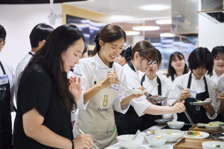 지난 22일 서울 중구 CJ더키친에서 진행된 ‘2026 CJ도너스캠프 문화동아리’의 요리부문 전문가 특강에서 이연주 셰프(사진 중앙)가 청소년들의 창작메뉴를 맛보고 있다. CJ나눔재단 제공.