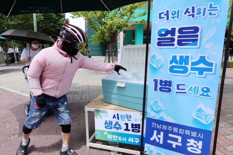 전남광주통합특별시 서구 치평동에서 시민들이 거리에 비치돼 있는 얼음물을 집고 있다. 연합뉴스