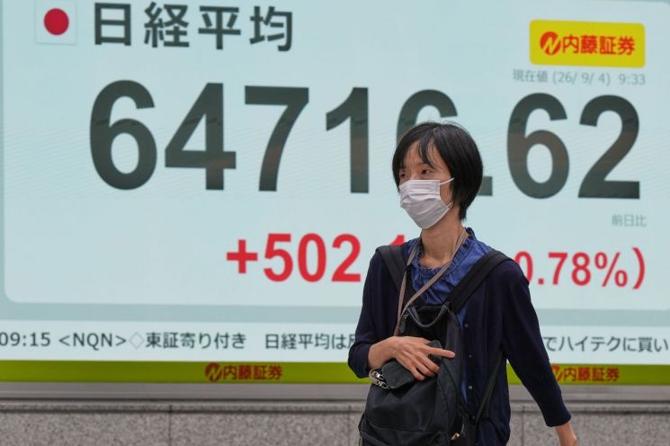 지난 4일 일본 도쿄의 증권사 건물 인근에서 한 시민이 닛케이225지수가 표시된 전광판 앞을 지나고 있다. 도쿄(일본)=AP연합뉴스.