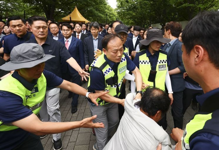 국회 국정조사특별위원회 위원들이 지난 7월2일 서울 송파구 올림픽공원 내 개표소 내부로 이동하는 도중 한 시위 참가자가 앞으로 달려들고 있다. 국회사진기자단
