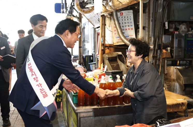 박완수 경남도지사(왼쪽)가 밀양아리랑시장에서 시장 상인과 악수하며 명절 인사를 건네고 있다. [사진제공=경남도]