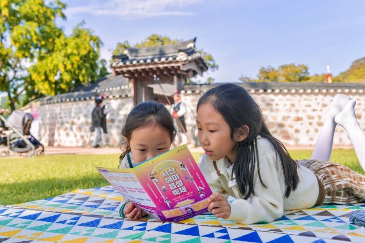 서산해미읍성축제장을 찾은 어린이들이 잔디 위에서 축제 프로그램 안내지를 살펴보고 있다. 올해는 관람객이 QR 호패를 발급받아 문·무과 시험 등에 참여하는 몰입형 역사체험을 선보인다. 서산문화재단