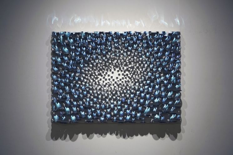 권용래의 ‘Light in Light-Blue’. 캔버스 위에 수많은 스테인리스스틸 유닛을 쌓아 빛이 반사되고 흩어지는 순간을 푸른색의 일렁이는 형상으로 만든 작품이다. 갤러리조은