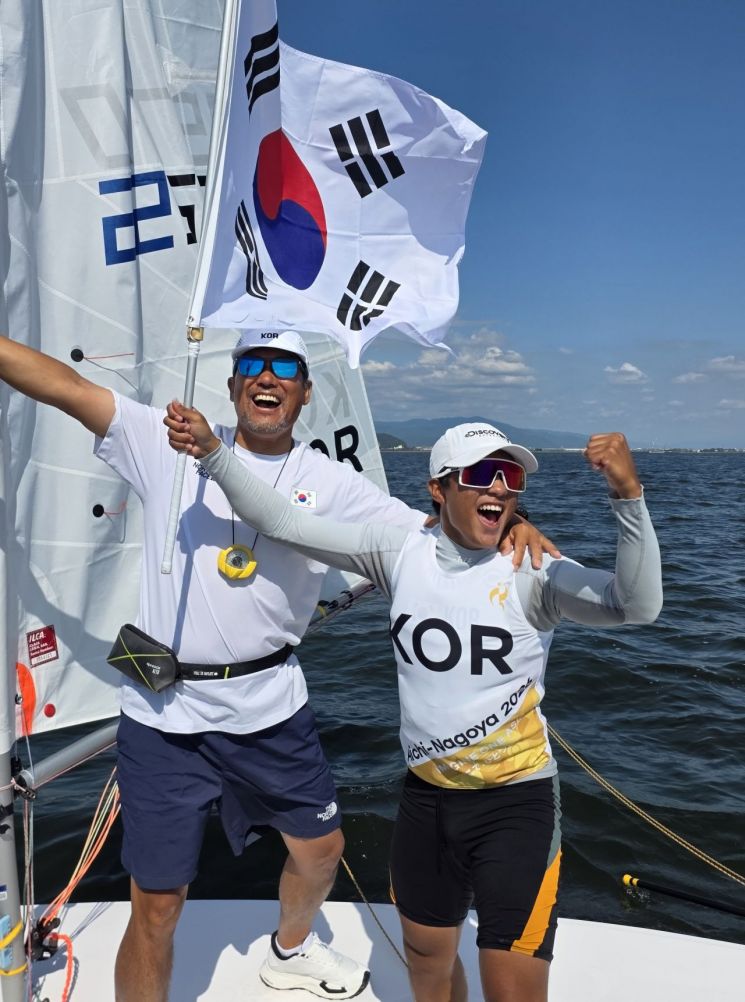 최지운(오른쪽)이 3일 일본 아이치현 가마고리 가이요 요트 항구에서 열린 2026 아이치·나고야 아시안게임 요트 소년부 딩기 경기에서 12차 레이스까지 치른 결과, 최종 25점을 기록해 1위에 올라 금메달을 확정한 뒤 환하게 웃고 있다. 연합뉴스