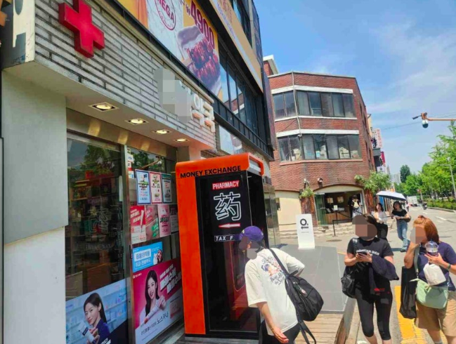 서울 마포구 홍대입구역 근처 약국 앞에 '무인 환전기'가 놓인 모습. 외국인 관광객들이 약국에 들어서고 있다. 연합뉴스