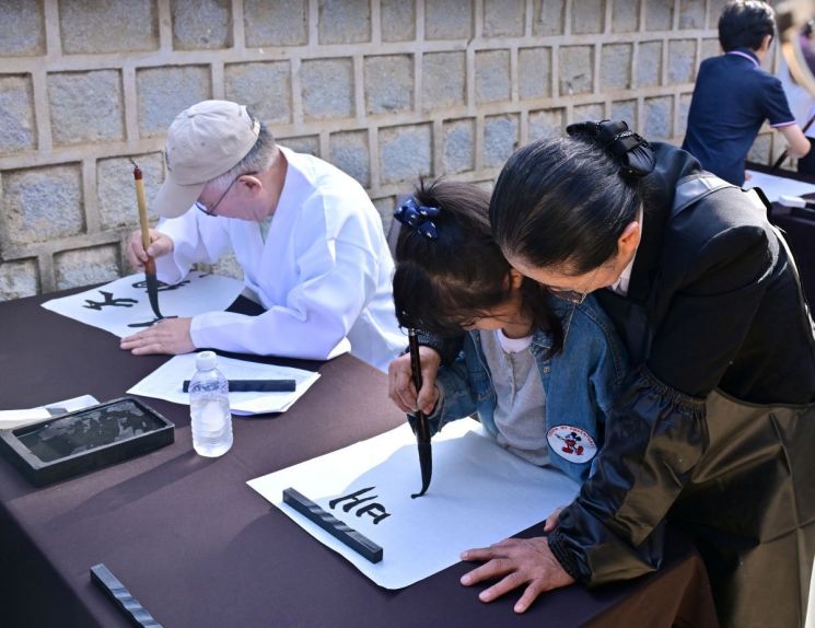 도산서원에서 열린 세계유산축전 붓글씨 체험에 참가한 어린이가 보호자의 도움을 받아 한 획씩 글씨를 써 내려가고 있다. 옛 서원의 ‘배움’이 오늘의 체험으로 이어지는 장면이다. 김기훈 작가