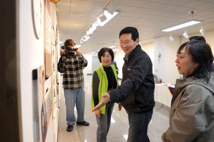 이상일 용인특례시장이 18일 수지구 상현2동 ‘제6회 소실봉 문화축제’에서 상현갤러리 수강생의 작품을 살펴보고 있다. 용인시 제공