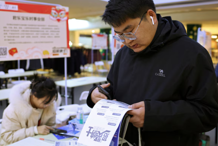 A college student looks at job postings at a job fair in Shijiazhuang, Hebei Province, China, on February 24, 2024. Reuters.