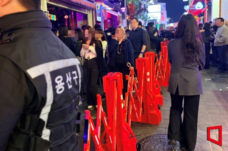 지난 24일 새벽 서울 용산구 이태원동 일대에 인파 이동을 안내하기 위한 바리케이드가 설치돼 있고, 용산구 관계자가 현장에서 보행 동선을 안내하고 있다. 이지예 기자