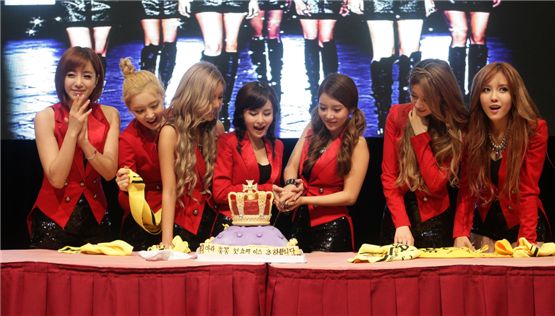 T-ara's Eunjung (left), Areum (second to left), Qri (third to left), Boram (center), Soyeon (third to right), Jiyeon (second to right) and Hyomin (right) cut a cake decorated with a crown at the group's first Hong Kong showcase opened at the Star Hall on September 18, 2012. [Core Contents Media]