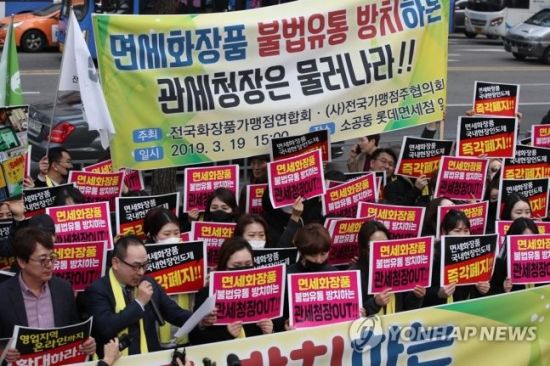 지난 19일 서울 중구 롯데면세점 앞에서 전국화장품가맹점연합회와 전국가맹점주협의회가 연 집회에서 참가자들이 면세화장품 국내현장인도제 즉각폐지 등을 요구하는 구호를 외치고 있다.