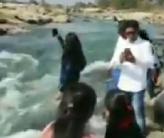 Woman taking a selfie in front of a famous waterfall in India and being caught by the rapids