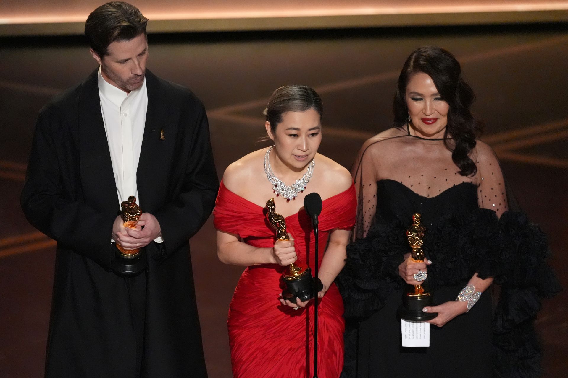 Director Maggie Kang, wearing a red dress, took the stage with the theme song Golden playing and held the trophy while on the verge of tears.